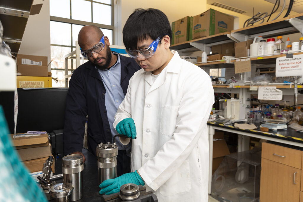 In the lab, Marcus Foston (left) and a collaborator (right) explore how to use lignin, looking at an lab instrument